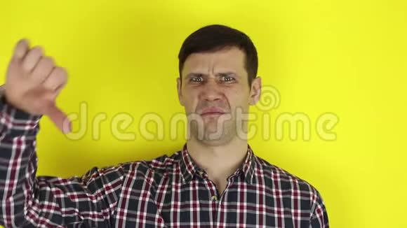 有趣的帅哥用拇指向下表达他的不满黄色背景上的肖像视频的预览图