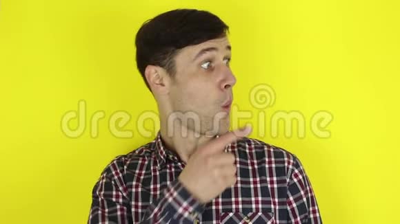 穿格子衬衫的帅哥把食指对着旁边黄色背景上的肖像视频的预览图