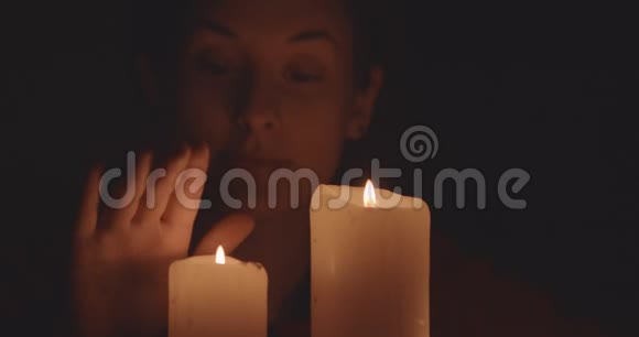 年轻女子触摸蜡烛黑暗中的火焰视频的预览图