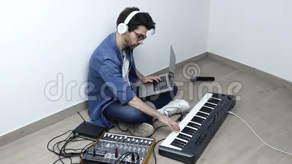 录音室的年轻人手持笔记本电脑的侧视与声音混合控制台一起使用视频的预览图