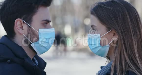 戴着医疗面具的男人和女人的户外肖像互相看着视频的预览图