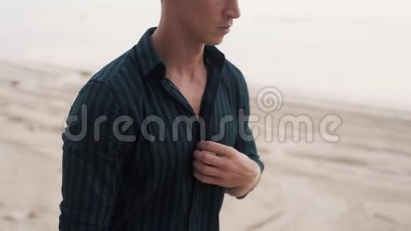 穿黑色衬衫的帅哥的肖像沿着沙滩散步视频的预览图