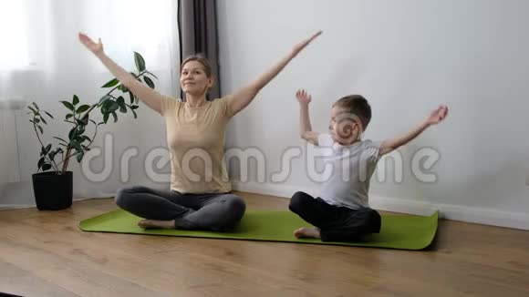 中年妇女妈妈和她的小儿子蹒跚学步的男孩一起在家做运动瑜伽练习健康生活方式视频的预览图