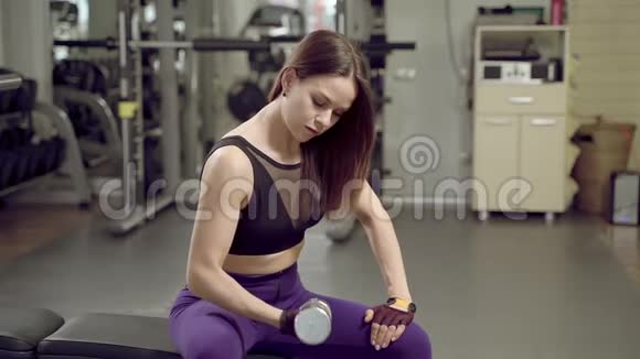 年轻有魅力的女人把哑铃放在一边在健身房锻炼后休息视频的预览图