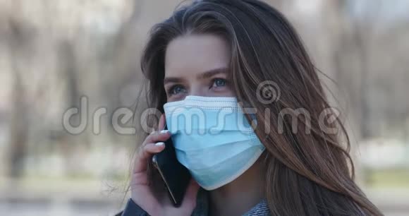 戴防护面具的年轻女孩在户外打电话视频的预览图