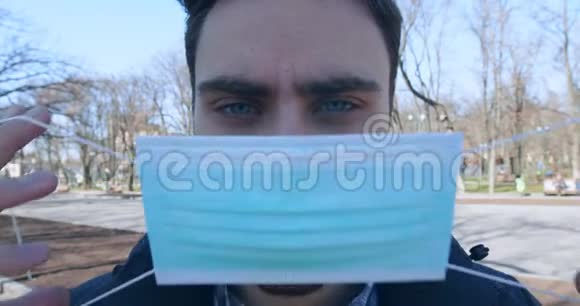 为冠状病毒防护戴上医用面罩的年轻人视频的预览图