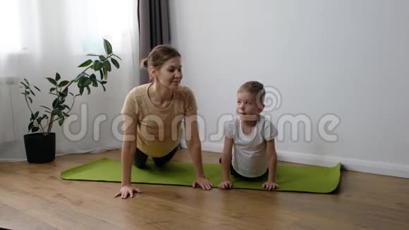 中年妇女的母亲和她的小儿子蹒跚学步的男孩一起在家做体育锻炼视频的预览图