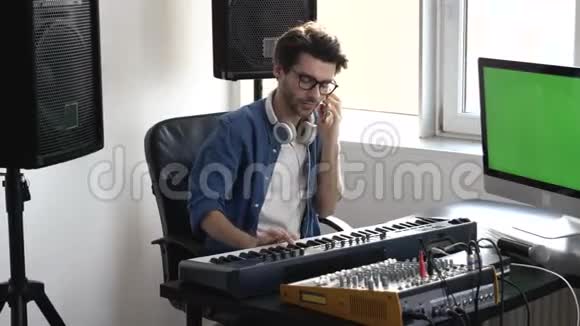 录音室的年轻人男人坐在键盘上在录音前调整声音控制台在电话里聊天绿色视频的预览图