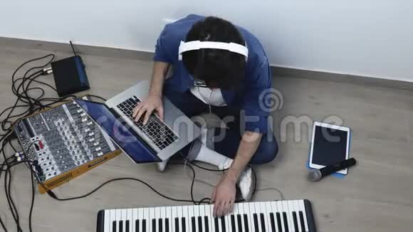 录音室的年轻人坐在地板上用笔记本电脑晃来晃去的家伙使用声音混合控制台视频的预览图