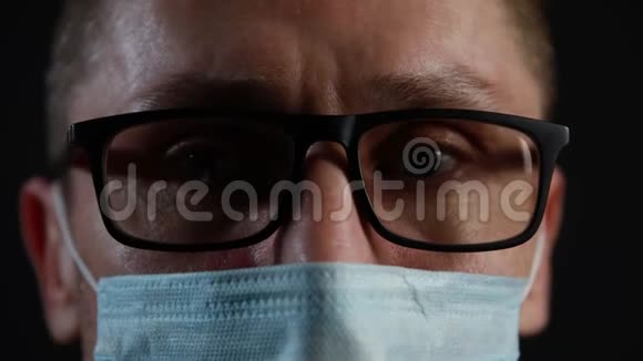 一个戴眼镜的男人的特写脸和一个黑色背景的医疗面具视频的预览图