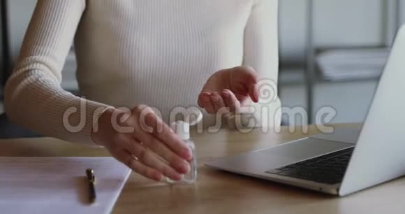 年轻女子在电脑远程工作前用洗手液擦手视频的预览图