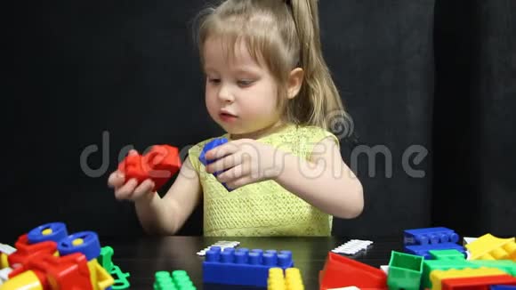 三岁的女孩在玩一个建设者的彩色积木孩子培养自己的思维能力发展和发展视频的预览图