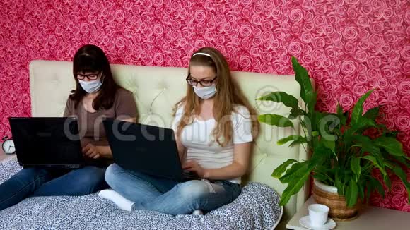 从家里远程工作两名白人女性一名年轻的金发女郎和一名戴防护口罩的成年人在笔记本电脑上工作视频的预览图