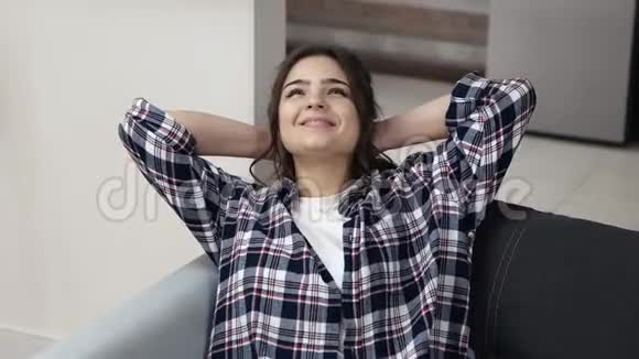 检疫期间厨房里的年轻女子手臂交叉在头后抬头看天花板微笑享受休息的女孩视频的预览图