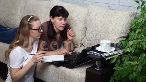 从家里远程工作两个女人一起在客厅沙发上用笔记本电脑工作讨论一个项目网上在线视频的预览图