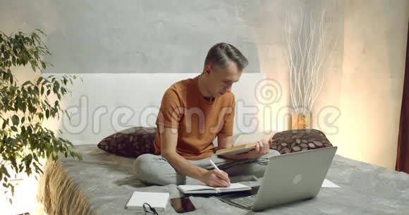 年轻人在家读书在笔记本电脑上做笔记网上学习视频的预览图