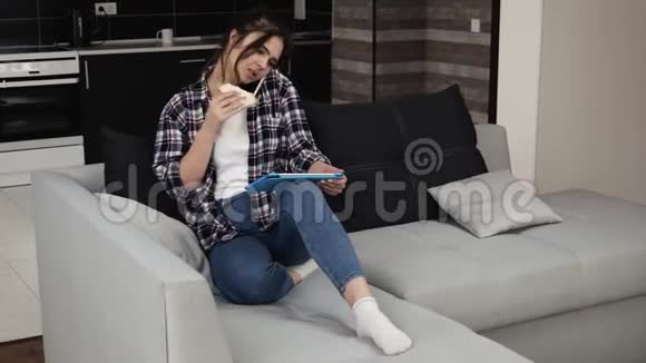 检疫期间厨房里的年轻女子用电话和平板电脑上网坐在沙发上视频的预览图
