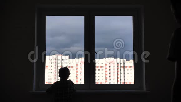 一位父亲和他的儿子在公寓窗户的背景下的剪影视频的预览图
