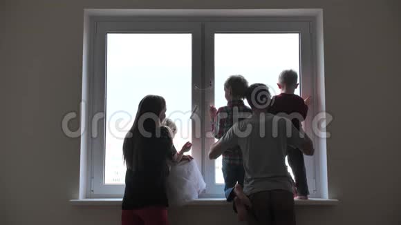 一个大家庭的剪影背景是一个新公寓的窗户视频的预览图