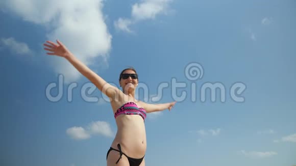 穿比基尼的苗条女孩站起来举起双臂享受假期视频的预览图