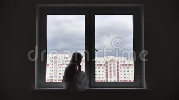 孤独的女孩子坐在窗外的窗台上视频的预览图