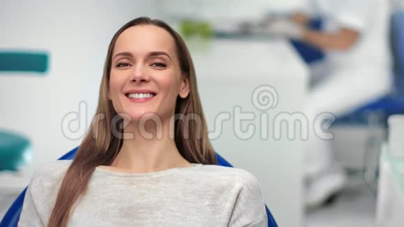 在牙椅上摆姿势的无忧无虑的女孩笑着长着白牙4k龙红相机视频的预览图