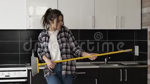 检疫期间厨房里的年轻女子独自站着假装像吉他一样在MOS上演奏玩得开心跳舞视频的预览图
