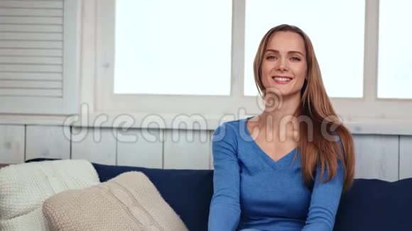 坐在沙发上的漂亮的家庭年轻女人的肖像中型摄影机视频的预览图
