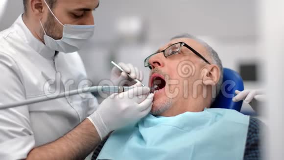 自信的男性牙医戴着保护面具与老年客户合作4K红色相机拍摄视频的预览图