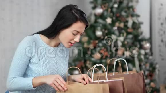 满意的美丽亚洲年轻女子打开购物袋与圣诞礼物4K红色相机拍摄视频的预览图