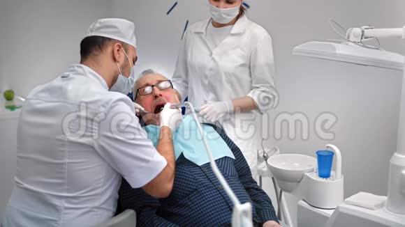 男性口腔医生与老年患者一起使用设备治疗牙齿4k龙红相机视频的预览图
