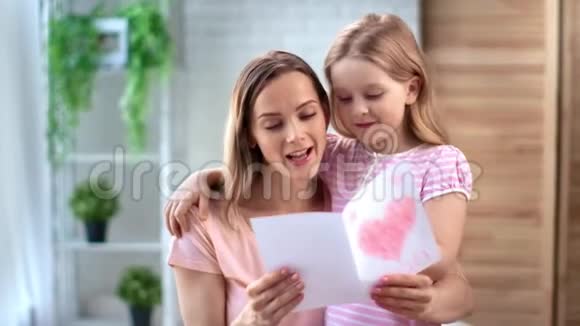 漂亮的小女孩用贺卡祝贺妈妈母亲节中型摄影机视频的预览图