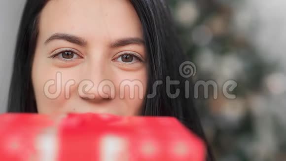 极端近脸滑稽的亚洲女人摆着喜庆的红色礼品盒4k龙红相机视频的预览图