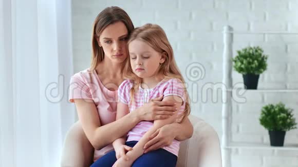 伤心的女人抱着心烦意乱的小女孩坐在家里拍摄红鸦4k影院视频的预览图