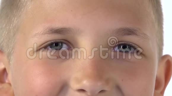 金发小男孩用明亮的眼睛直接看着相机惊讶地在白色的背景上闭上眼睛慢动作视频的预览图