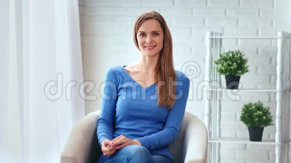 快乐的金发女孩在豪华的家庭内部放松坐在扶手椅上中型摄影机视频的预览图