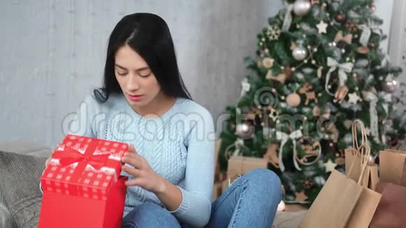 震惊的休闲亚洲女孩兴奋地打开了圣诞树附近的红色礼品盒4k龙红相机视频的预览图