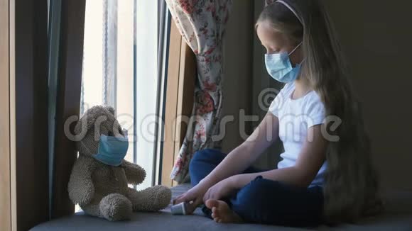 呆在家里检疫冠状病毒大流行预防伤心的女孩和他的玩具熊都戴着防护口罩视频的预览图