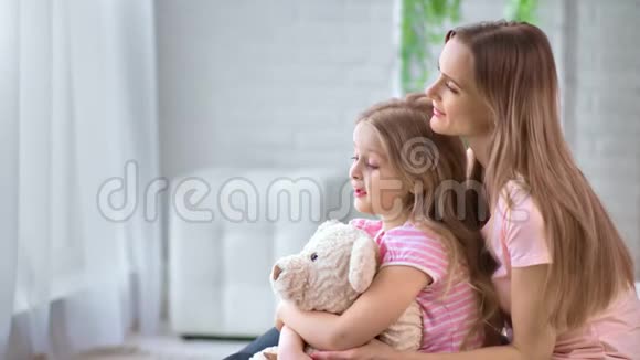 快乐的母女有着友好的交谈拥抱玩具熊中型摄影机视频的预览图