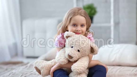 可爱的女孩拥抱玩具熊坐在舒适的卧室床上拍摄红鸦4k影院视频的预览图