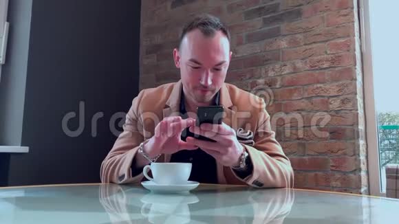 一个帅哥在咖啡馆里独自喝着大咖啡在智能手机上写字视频的预览图