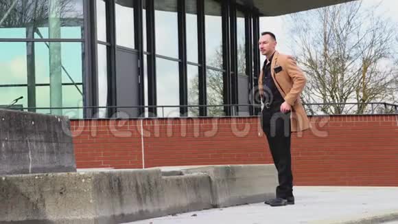一个穿着米色外套的男人在商务中心走来走去视频的预览图