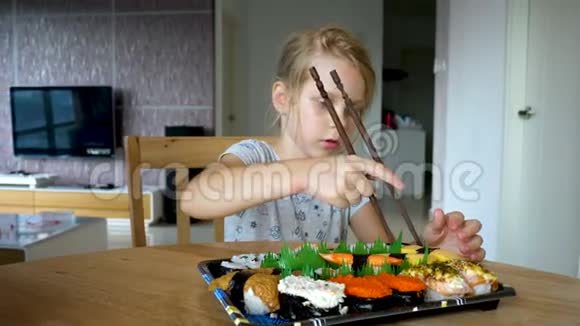 年轻女孩试着拿盘子里的寿司卷视频的预览图