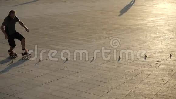 年轻的长发男子滑旱冰在城市公园的一个美好的夜晚在圆锥形之间跳舞自由式滚球式视频的预览图