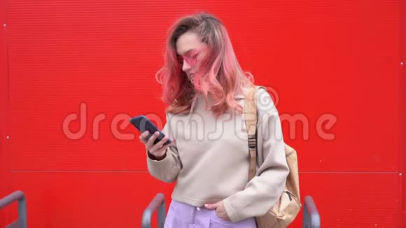 时尚肖像美丽的微笑时髦女人戴太阳镜红色头发与智能手机对抗视频的预览图