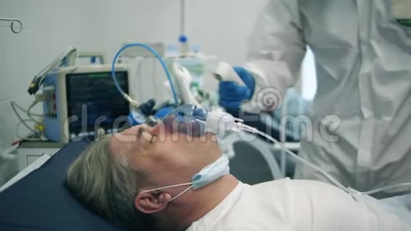 带氧气面罩的病人正在检查体温冠状病毒患者附近保护性医生视频的预览图