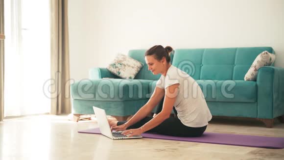 有魅力的年轻女性在家做瑜伽伸展瑜伽视频的预览图