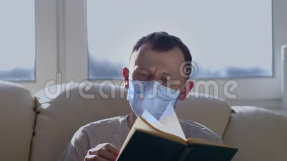 一个戴着医用口罩的年轻人坐在家里的沙发上看书视频的预览图