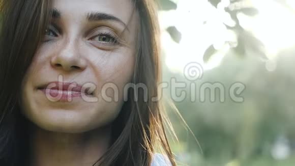 一个年轻女孩的可爱的脸绿色的眼睛背景在明亮的阳光背景美丽迷人的女孩视频的预览图
