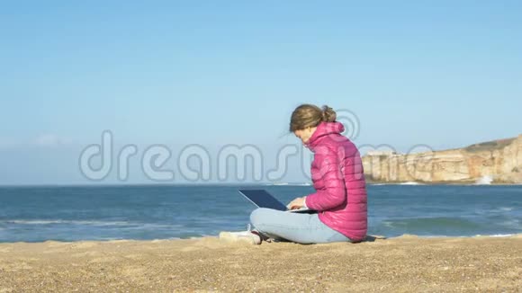 从冠状病毒中自我分离带笔记本电脑的年轻女自由职业者在海滩工作视频的预览图